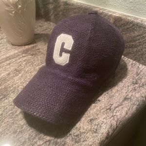 Blue baseball cap with leather strap in back.  Embroidered ‘C’ on front.